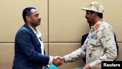 Pemimpin Koalisi Oposisi Sudan, Ahmad al-Rabiah (kiri) berjabat tangan dengan Wakil Kepala Dewan Transisi Militer Mohamed Hamdan Dagalo usai penandatanganan di Khartoum, Minggu (4/8). 