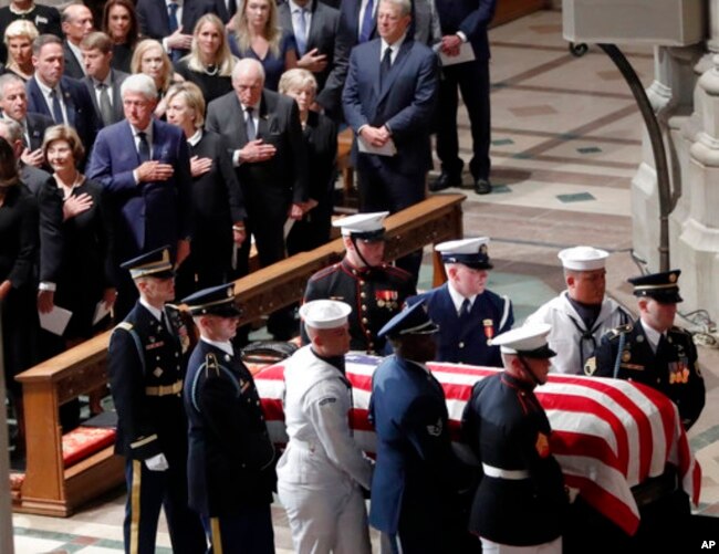 对参议员麦凯恩的隆重追悼会在华盛顿大教堂举行，麦凯恩参议员的灵柩抵达大教堂。前排左起：美国前第一夫人劳拉·布什，前总统比尔·克林顿，前国务卿希拉里·克林顿，前副总统迪克·切尼和他的妻子林恩，前副总统戈尔。