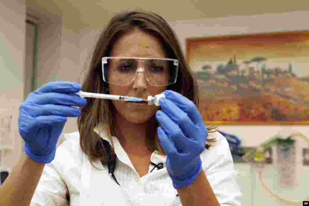 Dr Felicity Hartnell, membre de l&#39;équipe de recherche à la clinique de l&#39;Université d&#39;Oxford, tient un flacon d&#39;un vaccin expérimental contre le virus Ebola à Oxford, Angleterre mercredi 17 septembre 2014. (AP Photo / Steve Parsons / Pool) 