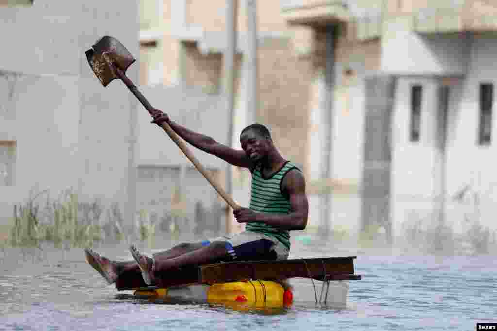 A resident uses a shovel to row through flooded streets after last week&#39;s heavy rains in Keur Massar, Senegal, Sept. 8, 2020.