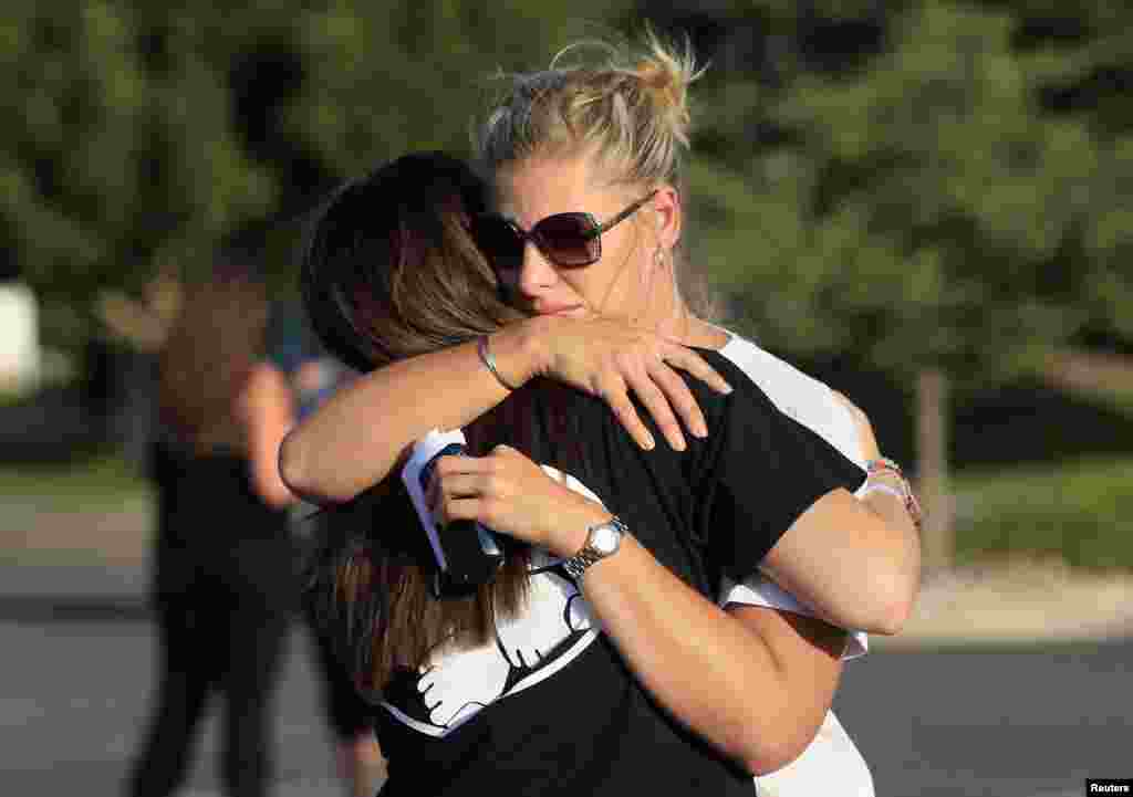 People embrace before a vigil for victims behind the theater where a gunman opened fire on moviegoers in Aurora, Colorado July 20, 2012. 