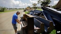 Wayne Christopher plays the keys on a piano put out on the curb in Port Arthur, Texas, Sept. 25, 2017, next to pews from the Memorial Baptist Church which he'd attended his whole life. 