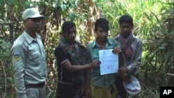 A ranger of Cambodia's 3,000 square kilometer Phnom Samkos Wildlife Sanctuary stands next to three Cambodian youth who were found entering the park illegally and made to agree not to enter again in the future, before they were released. The sanctuary lies