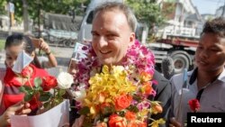 Aktivis hak buruh Inggris, Andy Hall (tengah) menerima rangkaian bunga dari para pendukungnya setibanya di Pengadilan Provinsi Phra Khanong di Bangkok, 29 Oktober 2014. (Foto: dok).