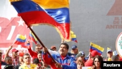 This Venezuelan government photo shows President Nicolas Maduro waving a flag to celebrate the anniversary the "Caracazo" revolutionary uprising; in a speech at the rally, he announced the arrest of a U.S. pilot for alleged spying, Feb. 28, 2015.