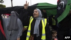 Libyans women, some wearing yellow vests, carry national flags as they chant slogans during a demonstration against strongman Khalifa Haftar in the capital Tripoli's Martyrs' Square on April 26, 2019. 