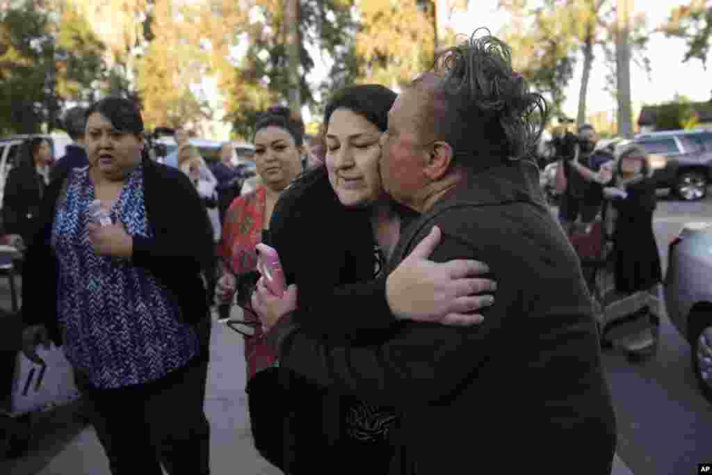 A woman who declined to give her name kisses her sister, center, a survivor of a mass shooting in San Bernardino, Calif., Dec. 2, 2015.