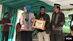 Ketua Bank Mata Jawa Barat Alma Lusiyati (kiri) memberikan penghargaan kepada perwakilan warga Tenjowaringin, kabupaten Tasikmalaya, yang menjadi donor mata dalam deklarasi desa siaga donor mata di desa tersebut, Sabtu (30/12/2018). (Foto: VOA/Rio Tuasikal)