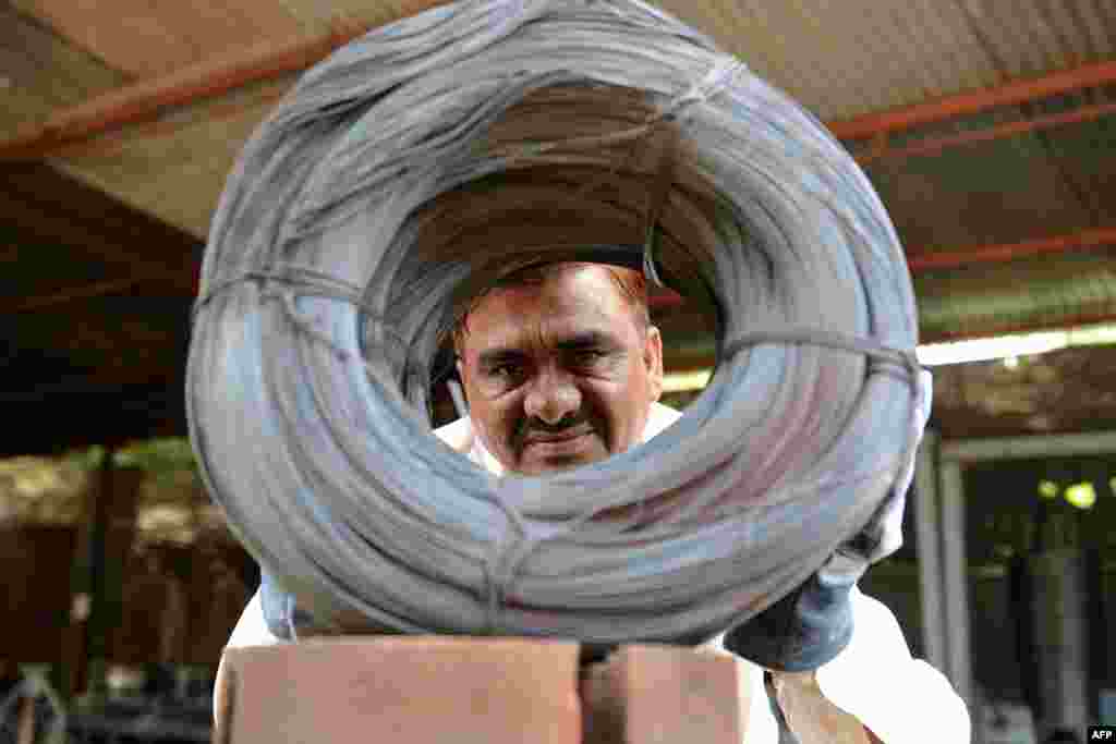 Indian owner of Bharat Industries, Niyazahmed Shaikh peers through coiled finished steel wires from scrap steel strips at his factory in Viramgam, some 60 kms from Ahmedabad. Bharat Industries at Viramgam makes recycled steel wires, used in the construction of buildings, nails, staple pins and so on, from scrap steel strips purchased from big steel manufacturing units from India and China.