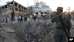 FILE - Security forces stand next to a crater created by a massive explosion that killed over 150, according to the Afghan president, in front of the German Embassy in Kabul, Afghanistan, May 31, 2017. The Taliban's second in command and head of the militant Haqqani network denied involvement in recent deadly attacks in Kabul and western Afghanistan.