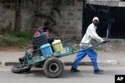 FILE - A water vendor with containers on his wheel cart attempts to deliver water in Nairobi, Kenya, July 10, 2009.