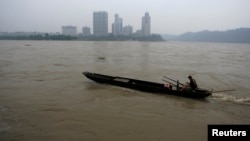 A fisherman drives his boat upstream at the junction of the Min and Dadu Rivers near the city of Leshan, Sichuan province, July 22, 2009. 