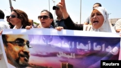 Protesters hold a picture of slain political activist Abdelsalam al-Mosmary during his funeral in Benghazi July 27.