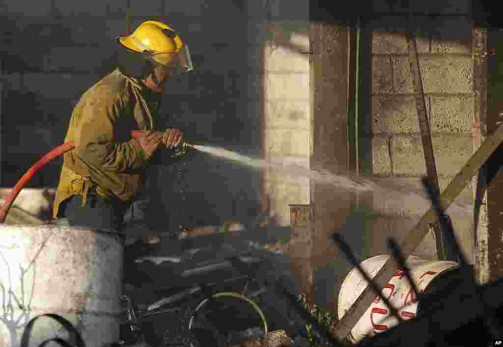 امدادی کارکن پانی سے آگ بجھانے میں مصروف ہے۔