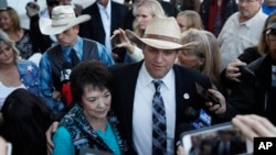 Ammon Bundy, right, and Carol Bundy, wife of Nevada rancher Cliven Bundy, speak with reporters outside a federal courthouse, Dec. 20, 2017, in Las Vegas. Chief U.S. District Judge Gloria Navarro declared a mistrial Wednesday in the case against Cliven Bundy, his sons Ryan and Ammon Bundy and self-styled Montana militia leader Ryan Payne. 