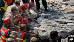 Pakistani Army troops and rescue workers struggle to recover a body in the rubble at the site of a suicide bombing in Shadi Khan, about 80 kilometers (50 miles) northwest from Pakistani capital, Aug. 16, 2015. 