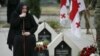 FILE - A woman mourns at the grave of a Georgian soldier killed during Georgia's conflict with Russia over the breakaway region of South Ossetia in 2008 during a ceremony at the memorial cemetery in Tbilisi, Georgia, Aug. 8, 2015. 