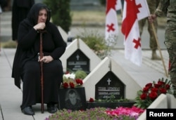 FILE - A woman mourns at the grave of a Georgian soldier killed during Georgia's conflict with Russia over the breakaway region of South Ossetia in 2008 during a ceremony at the memorial cemetery in Tbilisi, Georgia, Aug. 8, 2015.