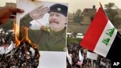 Un manifestante prende fuego a un poster de Izzat Ibrahim al-Douri, el oficial de más alto rango del régimen de Saddam Hussein que no fue nunca capturado tras la caída del régimen.