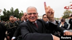 Former Tunisian Foreign Minister and presidential candidate Kamel Morjane, who served under ousted President Ben Ali, shows his ink-stained finger after voting at a polling station in Sousse, Nov. 23, 2014. 