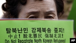 A North Korean defector holds a banner during a rally for North Korean refugees who were repatriated by the Chinese government, in front of the Chinese Embassy in Seoul, South Korea. (2011 File)