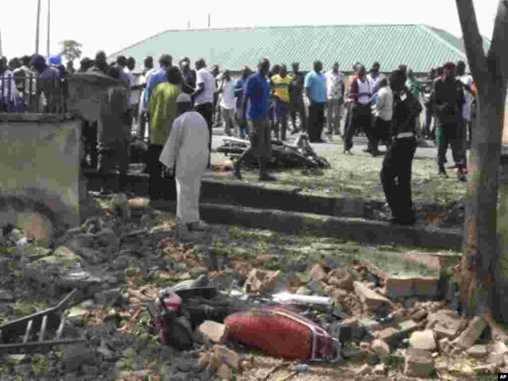 People gather at the site of a suicide bomb attack on the street in Jalingo, Nigeria Monday, April 30, 2012 . A motorcycle-riding suicide bomber drove into a convoy carrying a top police official in northeast Nigeria on Monday, detonating his explosives a