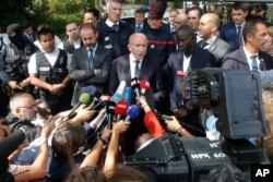 French Interior Minister Gerard Collomb, center, answers reporters after a knife attack Aug. 23, 2018 in Trappes, west of Paris.