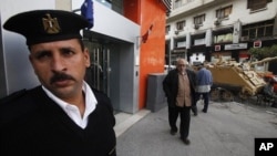 An Egyptian policeman stands guard outside a bank in Cairo February 20, 2011