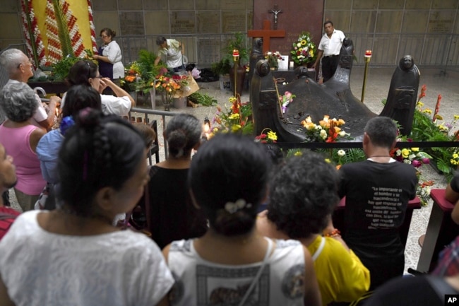 Fieles rezan frente a la tumba del arzobispo de El Salvador, Óscar Arnulfo Romero, en la catedral metropolitana de San Salvador, el 13 de octubre de 2018, un día después de que el asesinado arzobispo fuera elevado a la santidad junto con el papa Paulo VI y otros cinco beatos.
