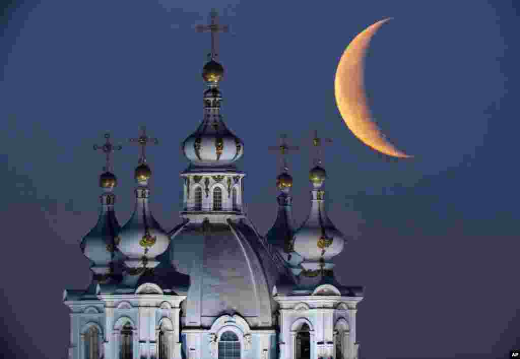 The moon rises in the sky above the domes of the Smolny Cathedral in St.Petersburg, Russia.