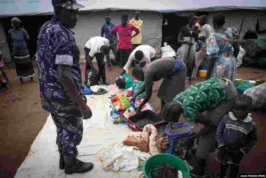 A Ugandan police officer inspects refugees' belongings to ensure there are no weapons.