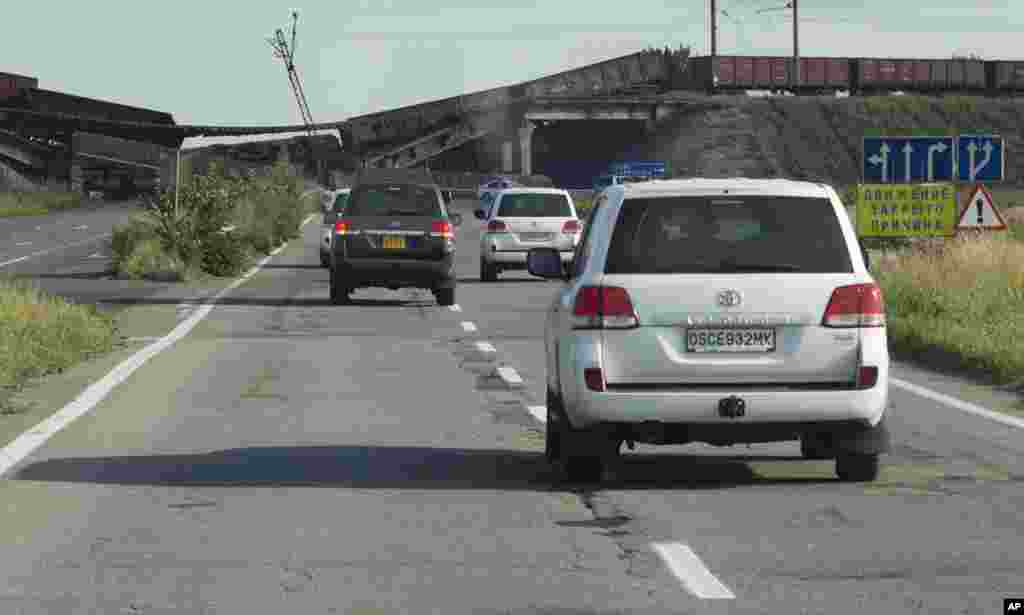 A convoy of International forensic experts and members of the OSCE mission in Ukraine approach an exploded bridge, outside Donetsk, eastern Ukraine, Aug. 3, 2014, as they travel to of the Malaysia Airlines Flight 17 plane crash site.