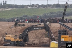 Israeli soldiers take position in front of Palestinian protesters as they gather at the Israel Gaza border, Nov. 16, 2018.