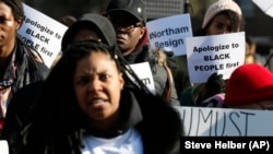 Demonstrators hold signs and chant outside the Governors Mansion at the Capitol in Richmond, Va., as they call for the resignation of Virginia Governor Ralph Northam after photo of a person wearing blackface was discovered in his medical school yearbook.