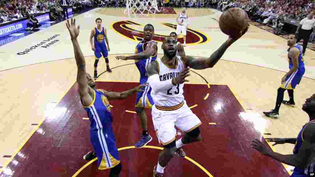 James LeBron (23) de Cavaliers de Cleveland marque un panier contre le défenseurs Andre Iguodala (9) &nbsp;de Golden State Warriors au cours de la première mi-temps du 6e match des finales de basketball de la NBA à Cleveland, mardi 16 Juin 2015.