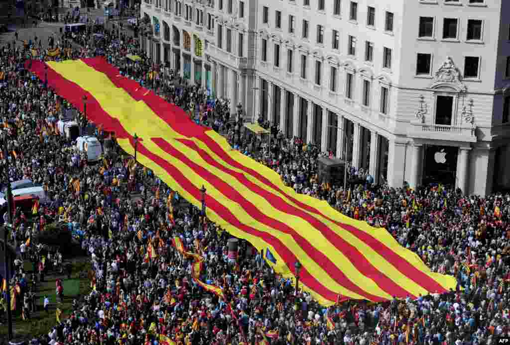Những người chống Catalan độc lập cầm một bích chương khổng lồ với cờ Catalan và cờ Tây Ban Nha trong một cuộc biểu tình tại quảng trường Catalunya ở Barcelona, Tây Ban Nha. Hàng chục ngàn người biểu tình tại Barcelona vì sự thống nhất Tây Ban Nha và chống lại Catalonia độc lập vào dịp lễ Quốc Khánh.