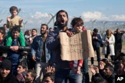 Người tị nạn bị mắc kẹt phản đối trước hàng rào dây kẽm gai ngăn cách biên giới Hy Lạp-Macedonia, ngày 27/2/2016.