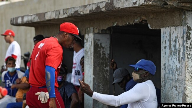 Cuban former baseball player Lazaro de la Torre, right, gives advice to a player after a game in Havana, Oct. 7, 2021. This year a record number of Cuban baseball players have defected abroad, while the island suffers its worst economic crisis in 30 years.