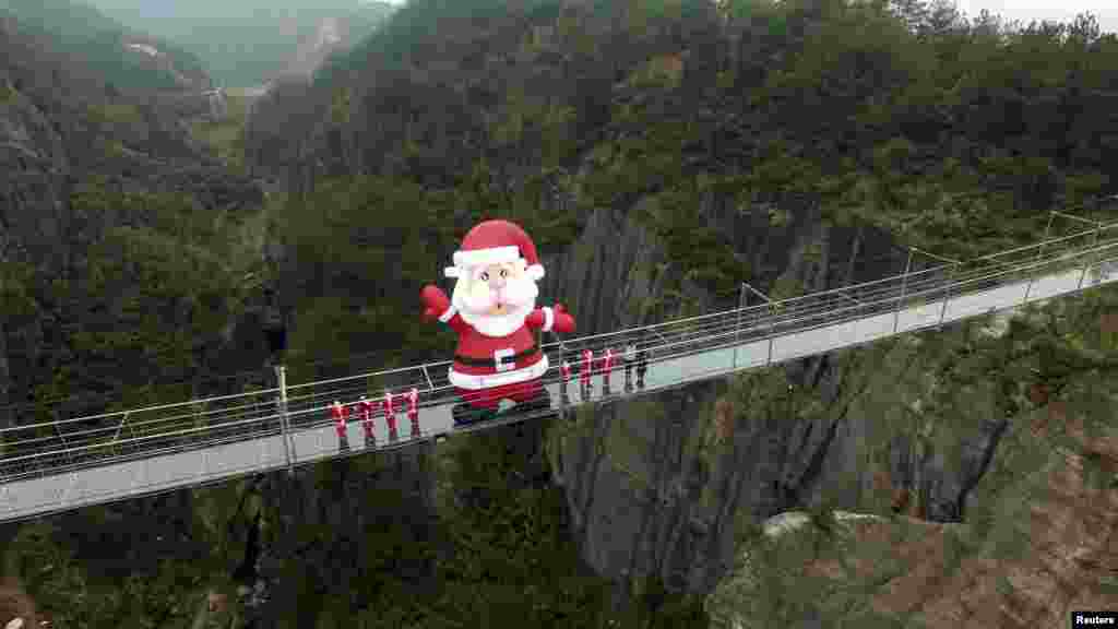 A giant inflatable Santa Claus is set up on a glass bridge during a promotional event to celebrate the upcoming Christmas, at Shiniuzhai tourist resort in Yueyang, Hunan province, China, Dec. 23, 2015.