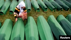 A Bosnian woman cries beside the coffin of a relative at the Potocari Memorial Center, near Srebrenica, July 11, 2013.