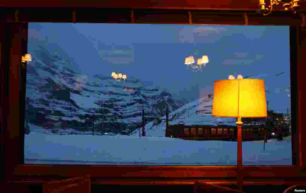 Gerbong kereta api Jungfraubahnen yang difoto melalui jendela hotel, terlihat setibanya di Stasiun Kleine Scheidegg di Wengen, Swiss. Sehari setelah Swiss National Bank memberitakan kejatuhan mata uang negara itu, para pengusaha hotel Swiss memperlihatkan kemarahan mereka melalui media sosial dan politisi mendesak pemerintah Swiss untuk mendukung industri pariwisata negara itu. &nbsp;