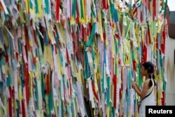 A girl looks at a barbed-wire fence decorated with ribbons bearing messages wishing for the unification between the two Koreas near the demilitarized zone separating the two Koreas in Paju, South Korea.