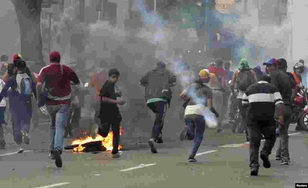 Supporters of opposition leader Henrique Capriles run away from tear gas fired by riot police as they demonstrated for a recount of the votes in Sunday's election, in Caracas, April 15, 2013.