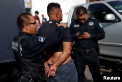 A migrant, who is part of a caravan traveling en route to the United States, is detained by police officers for being drunk outside a shelter in Tijuana, Mexico, Nov. 17, 2018.