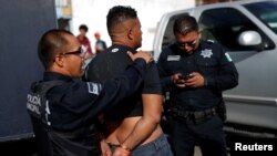 A migrant, who is part of a caravan traveling en route to the United States, is detained by police officers for being drunk outside a shelter in Tijuana, Mexico, Nov. 17, 2018.