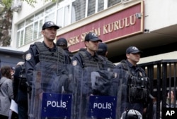 Riot police stand guard as hundreds of people queue in front of Turkey's Supreme Electoral Board in Ankara, Turkey, Tuesday, April 18, 2017.