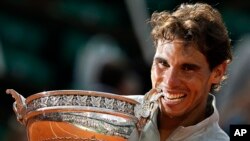 Spain's Rafael Nadal bites the trophy after winning the final of the French Open tennis tournament against Serbia's Novak Djokovic at the Roland Garros stadium, in Paris, France, Sunday, June 8, 2014. 