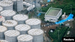 An aerial view shows workers wearing protective suits and masks working atop contaminated water storage tanks at Tokyo Electric Power Co. (TEPCO)'s tsunami-crippled Fukushima Daiichi nuclear power plant in Fukushima, August 20, 2013.