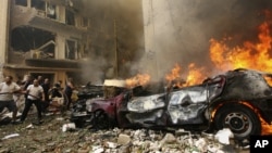 Firefighters try to extinguish a fire as a car burns at the scene of the car bomb explosion in Ashafriyeh, central Beirut, October 19, 2012. 
