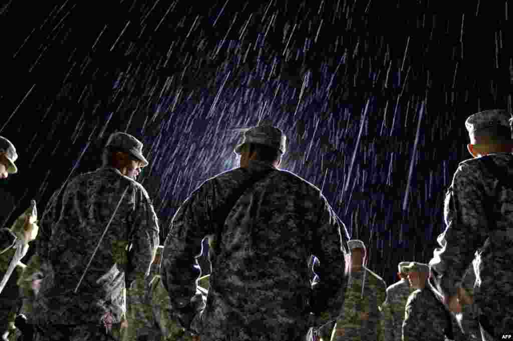 August 10: 1st Lt. Nikesh Kapadia, center, with the U.S. Army's 4th Brigade Combat Team out of Fort Campbell, Ky., stands in the rain waiting to go through customs at the Transit Center in Manas, Kyrgyzstan, on the way home after completing a deployment i
